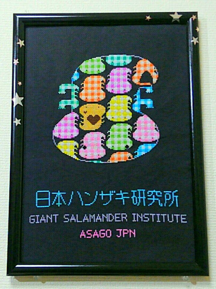 色とりどりのオオサンショウウオを大きな一匹の姿に配した日本ハンザキ研究所の刺繍